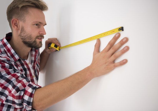 A man measuring a wall with a tape measure